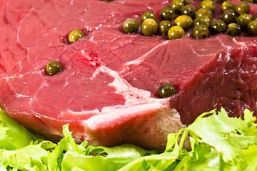 Closeup of raw beef decorated with green pepper grains