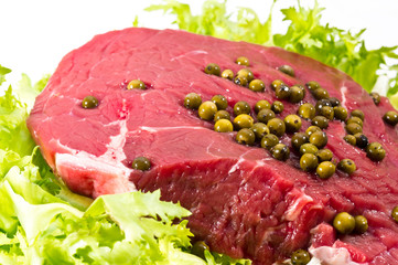 Closeup of raw beef decorated with green pepper grains