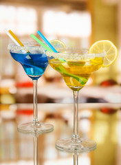 Yellow and blue cocktails in glasses on room background
