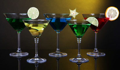 Alcoholic cocktails in martini glasses on dark yellow