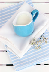 Blue jug with milk on napkin on wooden picnic table close-up