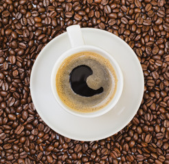 Cup of black coffee over bean covered background