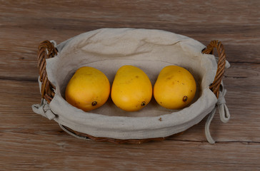 three mango in brown wicker basket isolated closeup