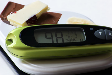 chocolate and glucometer on white background