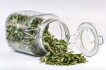 Glass container with a tea leaf spilled on table