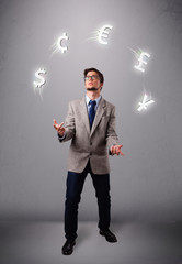 young man standing and juggling with currency icons