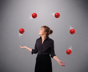 young girl standing and juggling with red balls