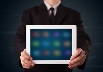 Businessman holding a white modern tablet with blurry apps