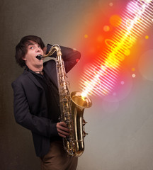 Fototapeta na wymiar Młody mężczyzna gra na saksofonie w kolorowe fale d¼więkowe