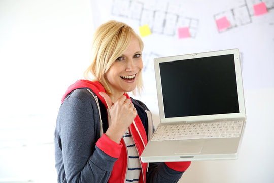 Young woman with laptop showing thumb up