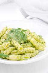 pasta penne with sauce of arugula and green peas closeup