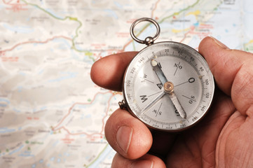 Hand holding compass, map (out of focus) in the background