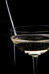 Glass of champagne and bottle infront of black background