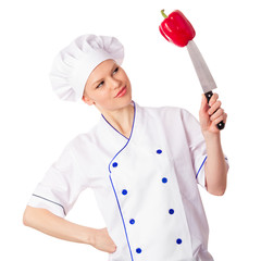 Pretty young chef woman cook in chefs cap looking at the pepper