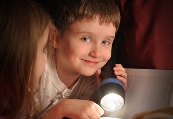 Boy Reading Book at Night with Flashlight