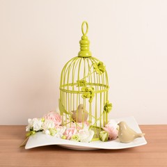 Cage à oiseaux décorative avec petits oiseaux en porcelaine et rose.