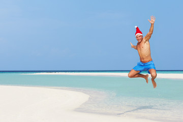 Man Jumping On Beach Wearing Santa Hat