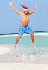 Man Jumping On Beach Wearing Santa Hat