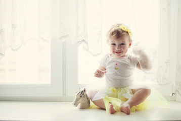 smiling baby girl sitting near the window