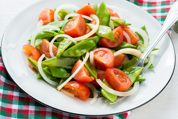 Fresh snow peas and tomato salad on plate