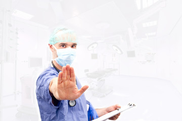 A doctor  making a stop sign in operating room background - focu