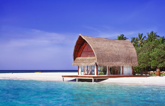 Landscape photo of beach house in Maldive ocean with blue sky