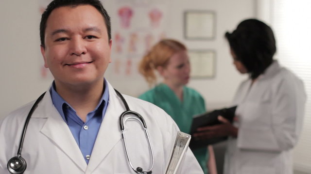 Confident male doctor, nurse and doctor in background