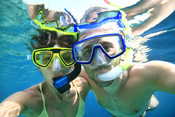 Woman and man doing snorkeling in the blue sea