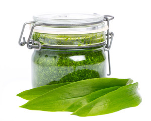 Bärlauchblätter vor einem Glas mit Bärlauchpesto