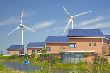 Roof with solar panels and wind turbines in the background