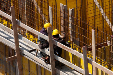 Specialists carpenters work on reinforcement armor at construction site with individual protections