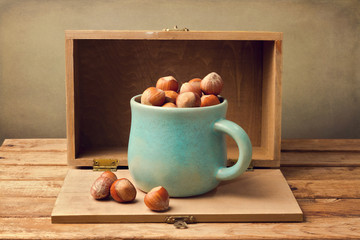 Hazelnuts in cup over wooden background