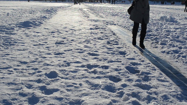 woman slide frozen ice field lake winter evening sulight shadows