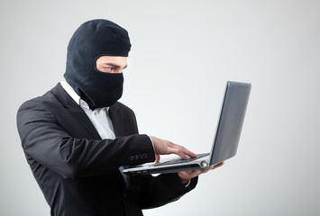 Portrait of a hacker with balaclava against grey background