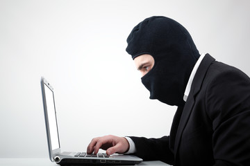 Portrait of a hacker with balaclava against grey background