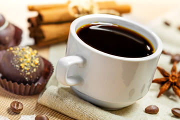Coffee cup, beans, candy, cinnamon and anise on a table