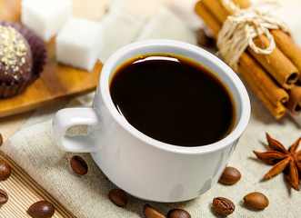Coffee cup, beans, candy, cinnamon, sugar and anise on a table