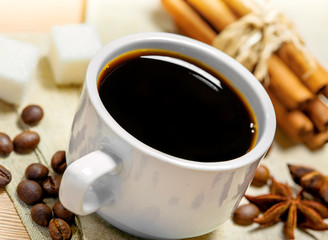 Coffee cup, beans, cinnamon, sugar and anise on a table