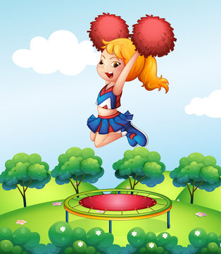 A cheerdancer holding her red pompoms above the trampoline