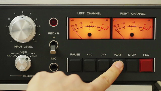 Finger pushing the play and stop button on vintage tape recorder