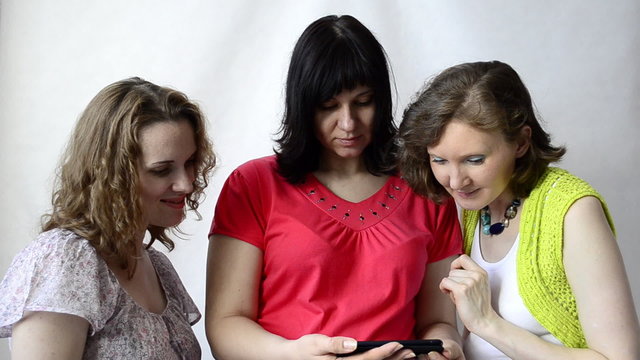 Three pregnant women look at photos of the smartphone