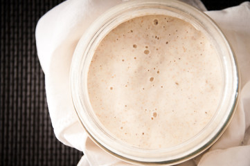 Sourdough in a glass jar on dark table mat (top view) - 51332862