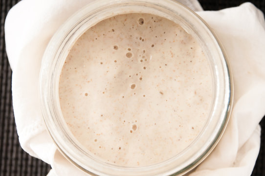 Sourdough in a glass jar on dark background (top view)