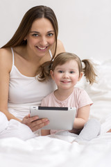 Little girl using tablet with her mother smiling