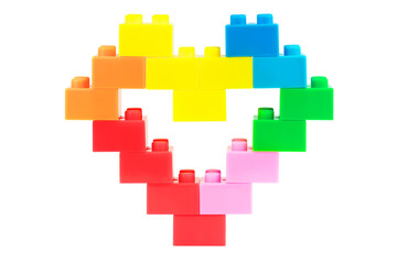 Heart made from plastic toy blocks on white background