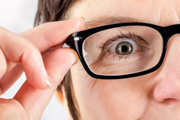 Woman holding glasses to see better