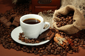 cup of coffee and coffee beans on brown background