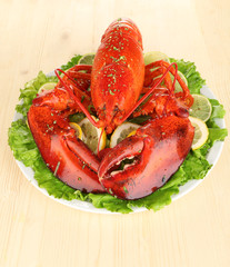 Red lobster on platter with vegetables on wooden table close-up
