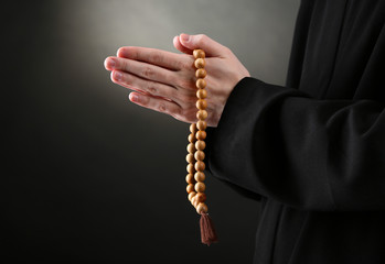 Priest holding rosary, on black background