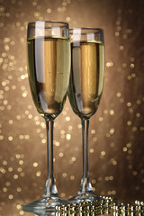 Two glasses of champagne on bright background with lights